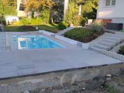 Poolumrandung mit Steinstelen und Blockstufen